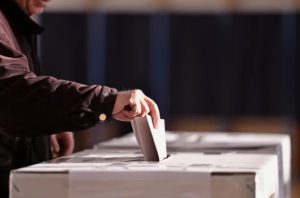 person putting ballot in a box