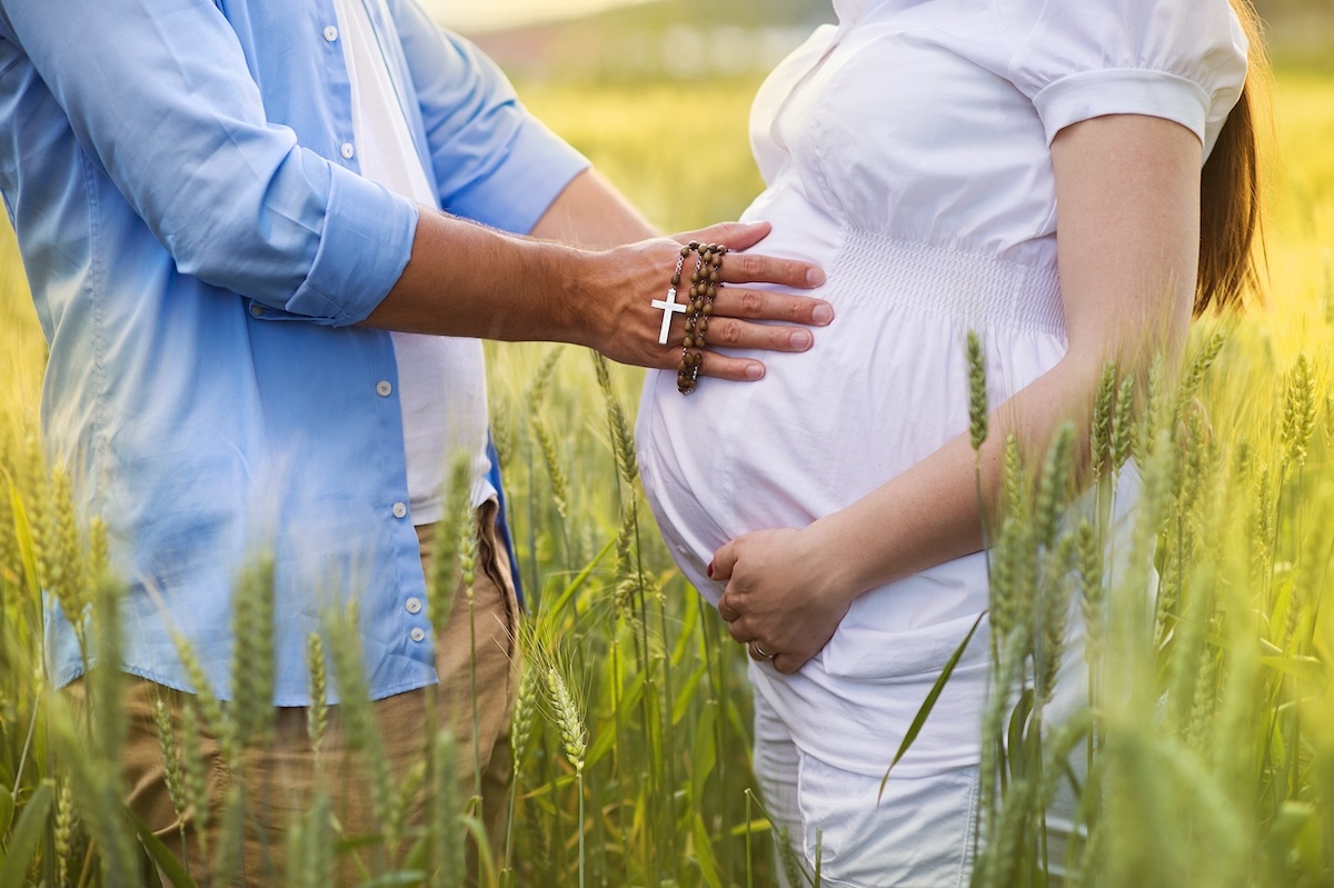 man placing hand on belly of pregnant woman