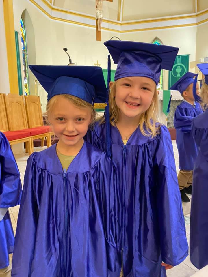 two school girls in graduation gowns smiling