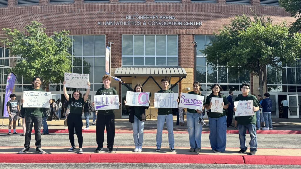 Catholic youth holding welcome signs in a parking lot