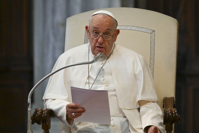 Pope Francis speaking at microphone with a document in his hand