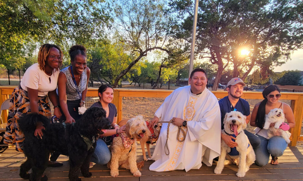 Fr. Brian Garcia posing with Catholic students and dogs