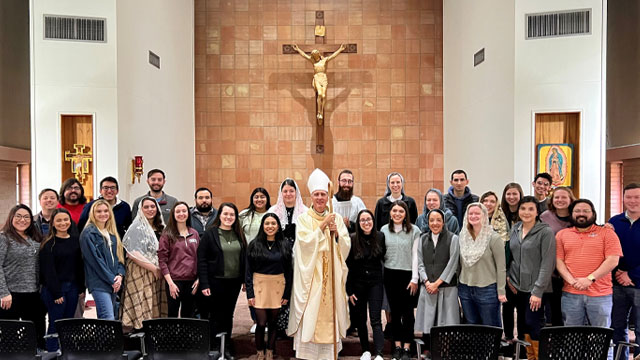 Bishop Gary with Young Adults standing in front of the altar at Mass