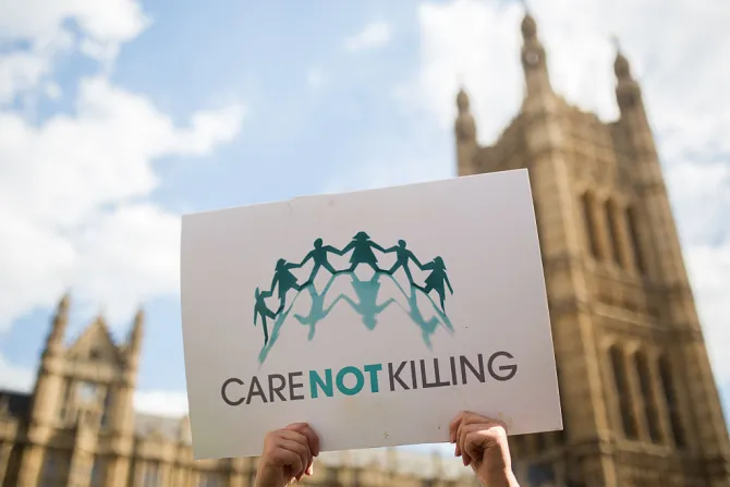 Campaigners against assisted dying gather outside the Houses of Parliament holding a protest sign