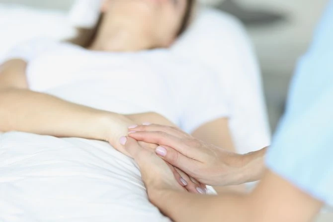 A caretaker and patient holding hands