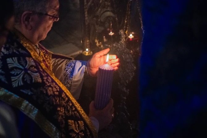 The custos of the Holy Land, Father Francesco Patton, lights the first candle of the Advent wreath at the site of the manger inside the Nativity Grotto